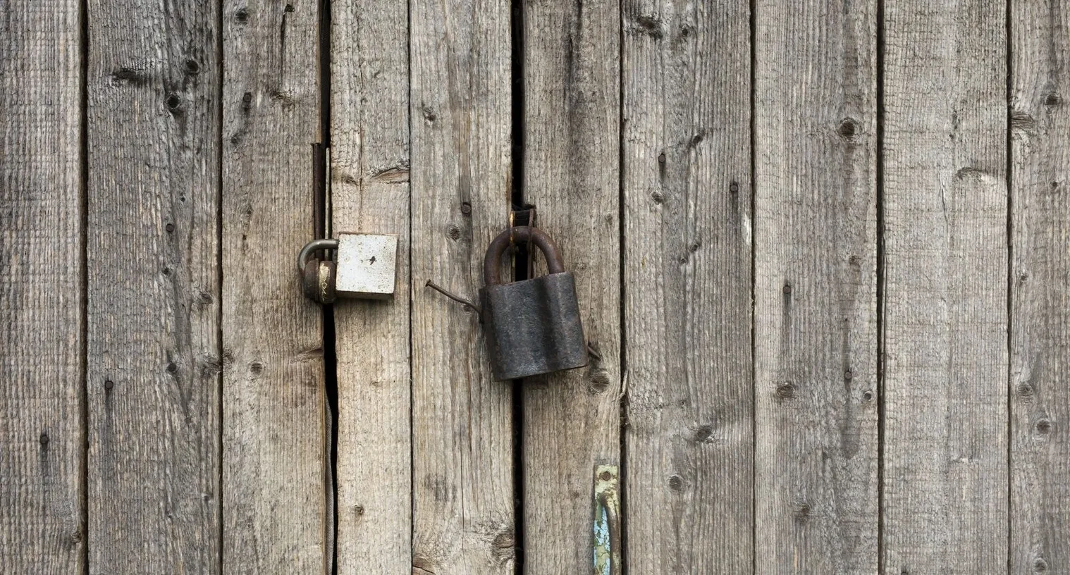 A heavy iron padlock and chain securing a wooden door