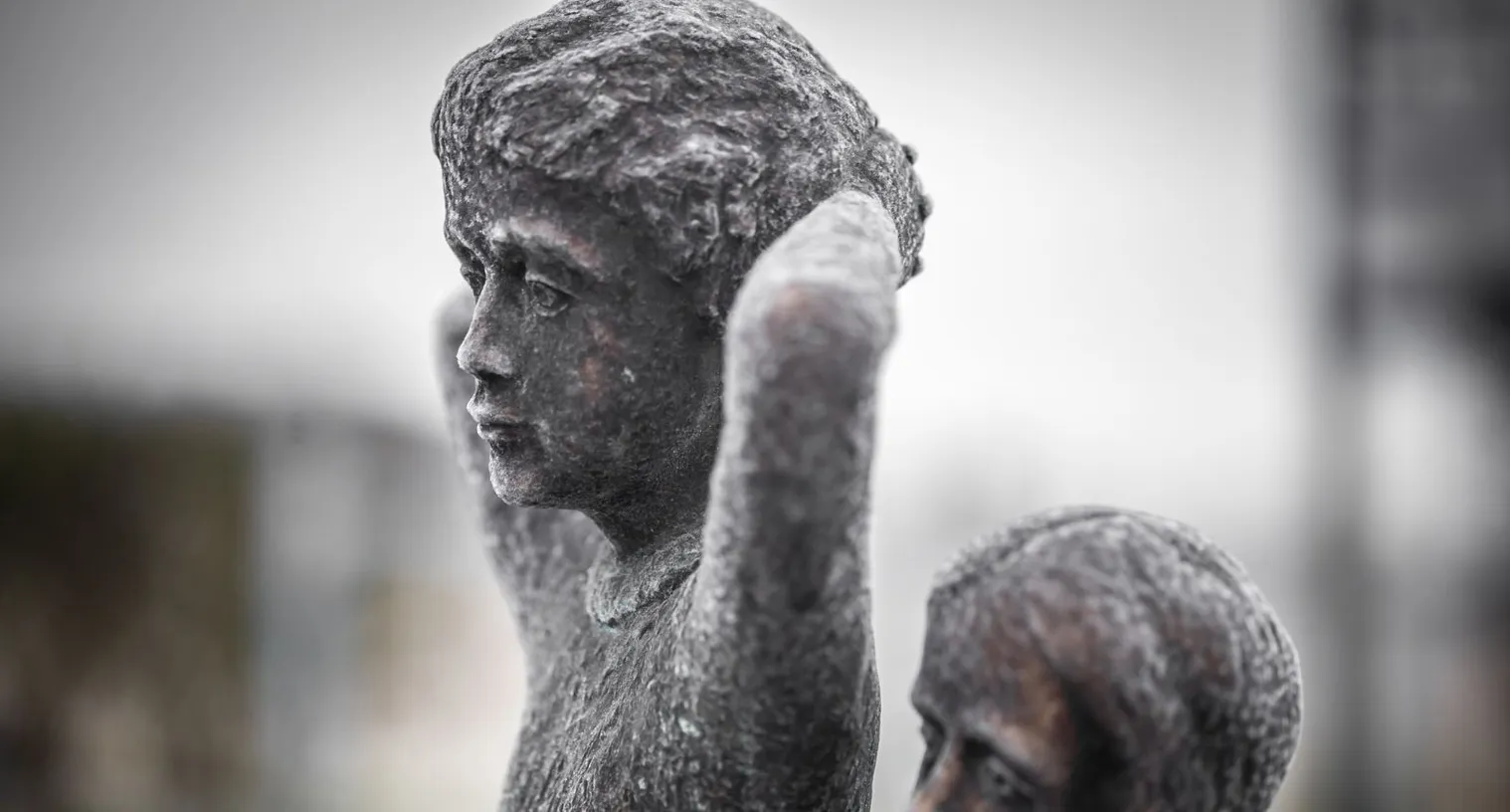 Rows of weathered bronze faces, wanted statues carved in stone