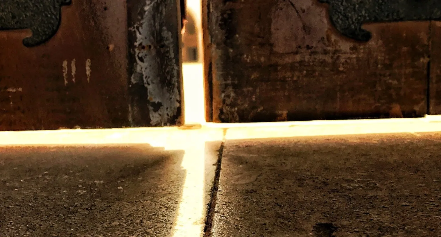 A thin blade of light glowing beneath a closed door